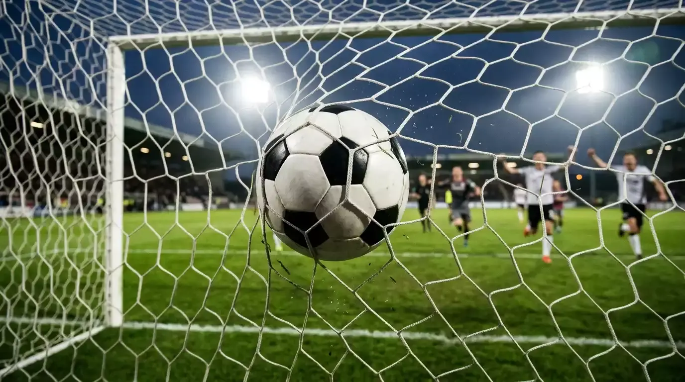 Detail fotbalového míče v síti branky při gólu na osvětleném stadionu