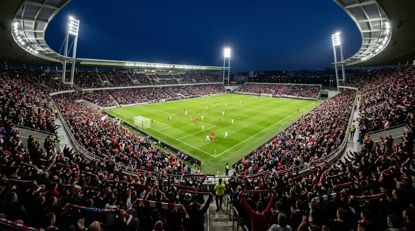 Zaplněný fotbalový stadion při večerním zápase pod umělým osvětlením